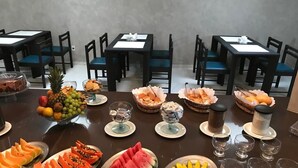 A dining table with various fruits and desserts, surrounded by black chairs and tables. - Happy Hotel Pajuçara (Maceió)