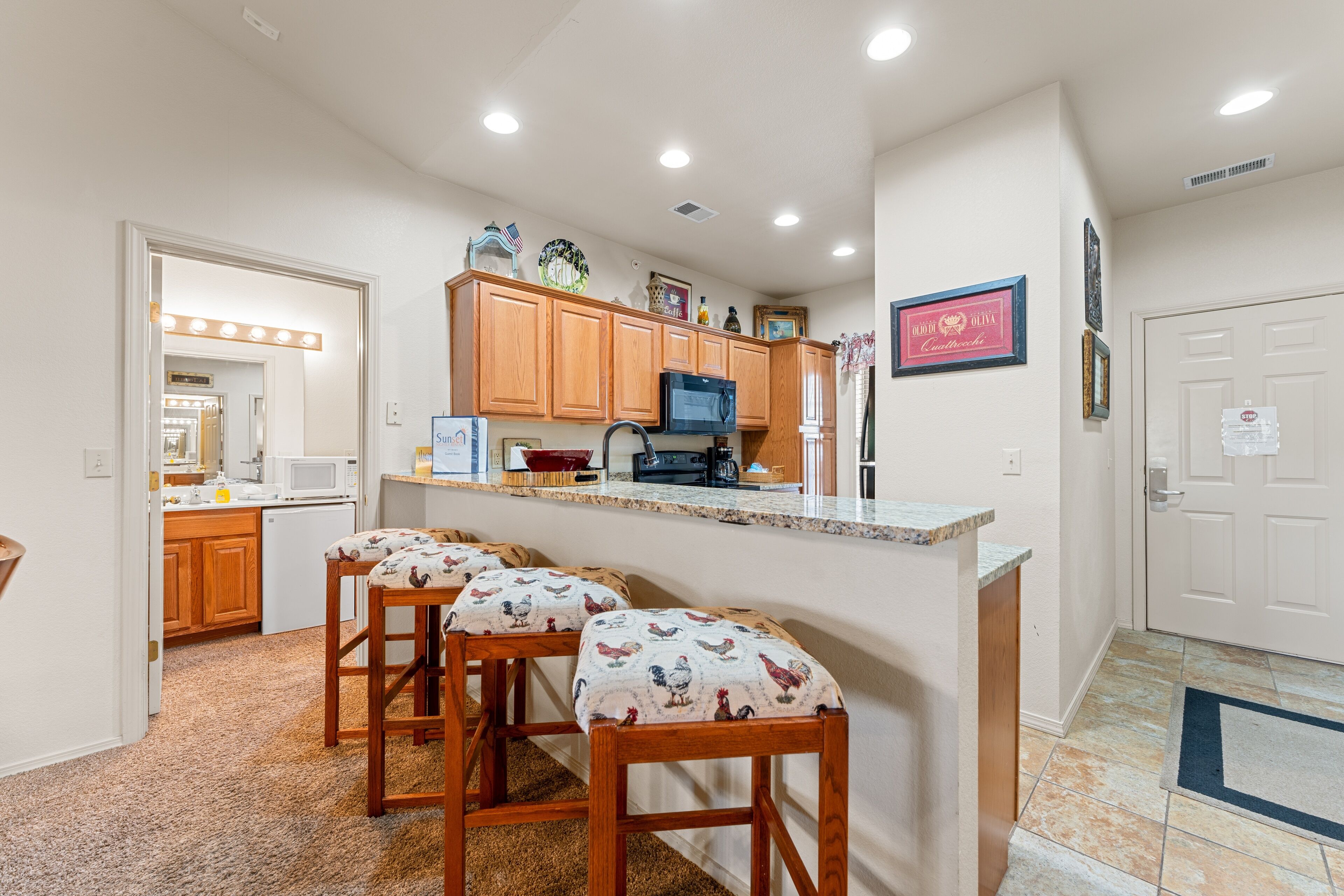 A kitchen with wooden cabinets, a countertop, and a bar stool area.