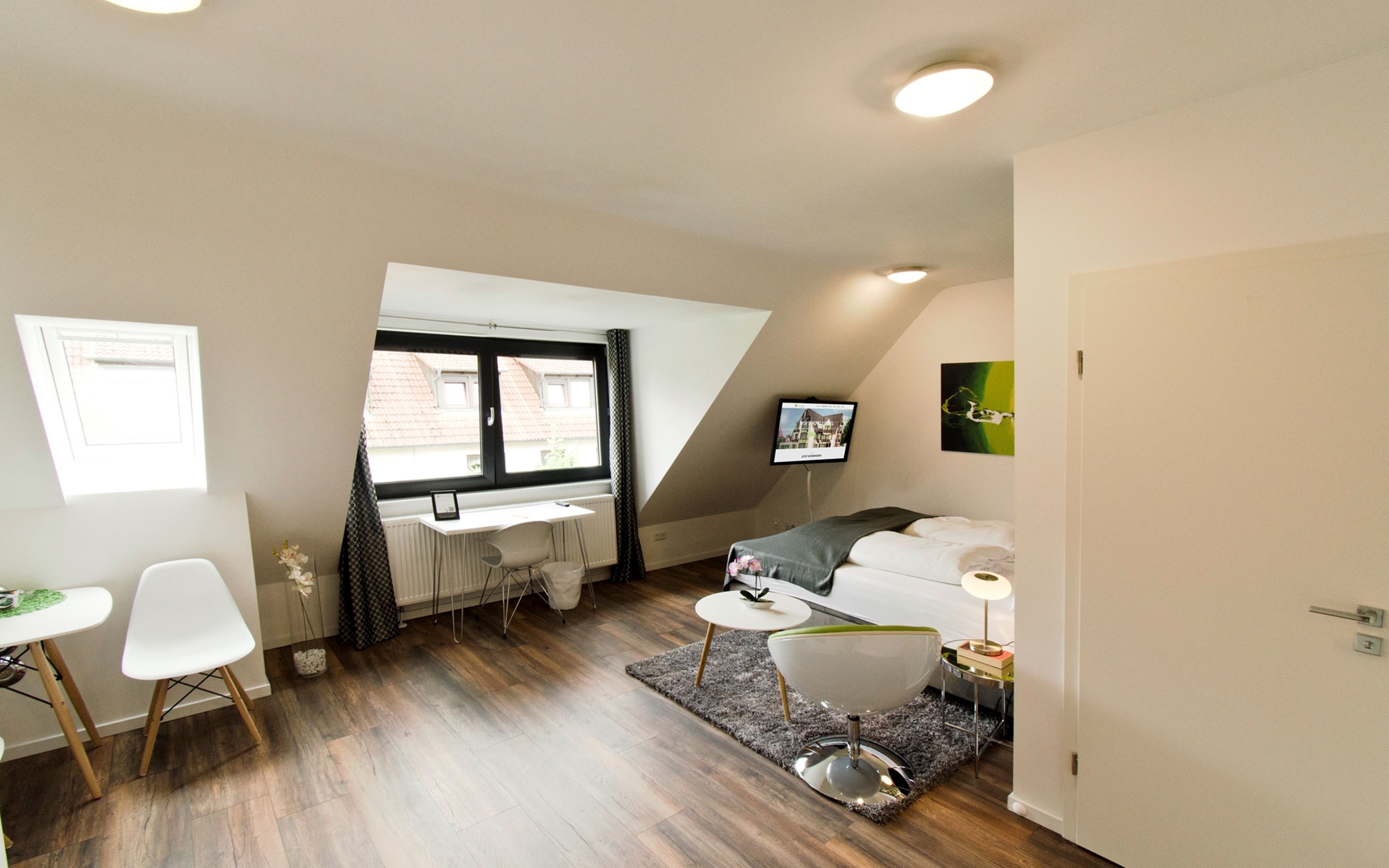 Una habitación moderna y luminosa con escritorio, cama y zona de comedor.