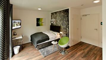Een moderne hotelkamer met een bed, een bureau, een stoel en een groot raam.
