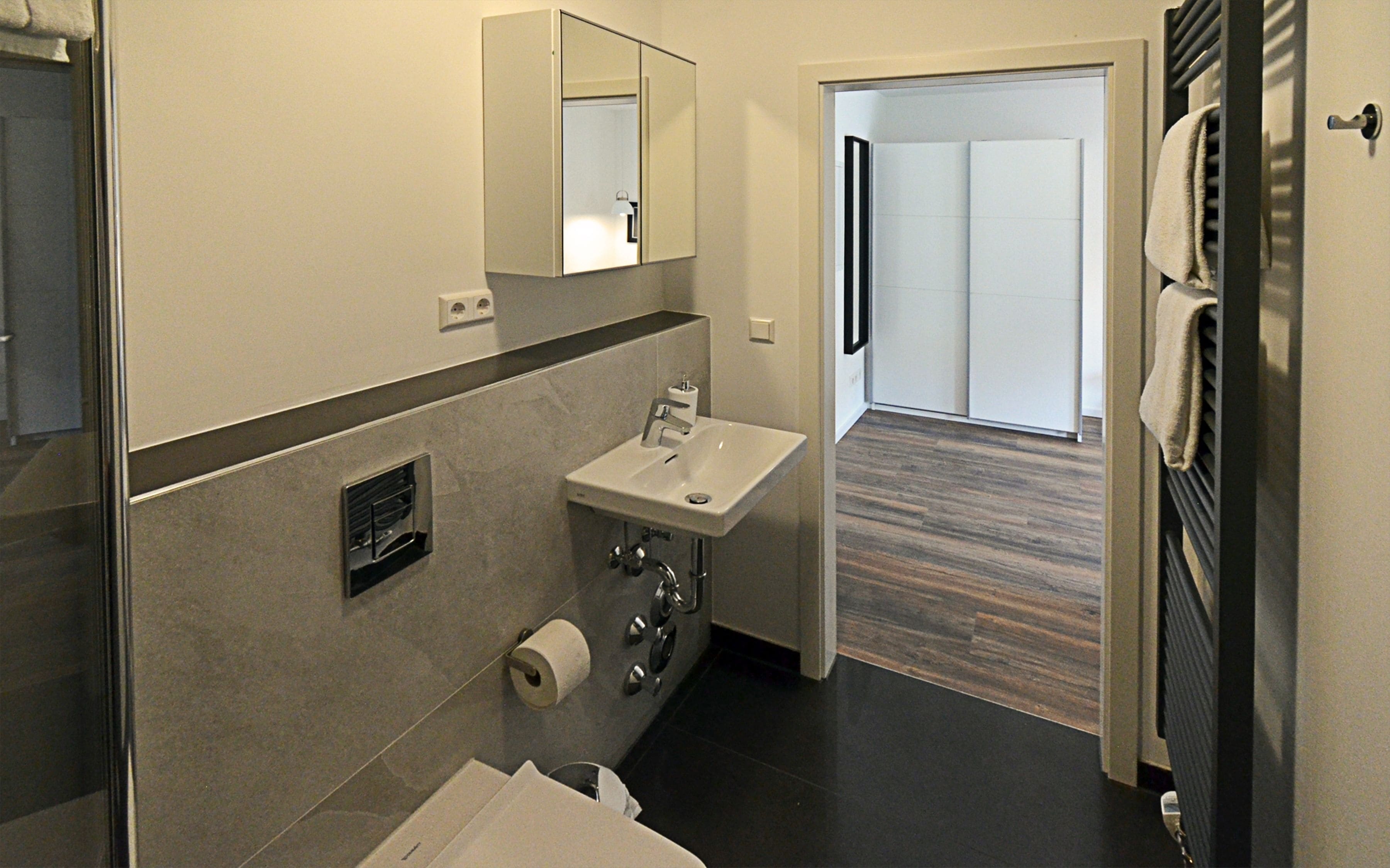 A modern bathroom with a sink, mirror, and toilet.