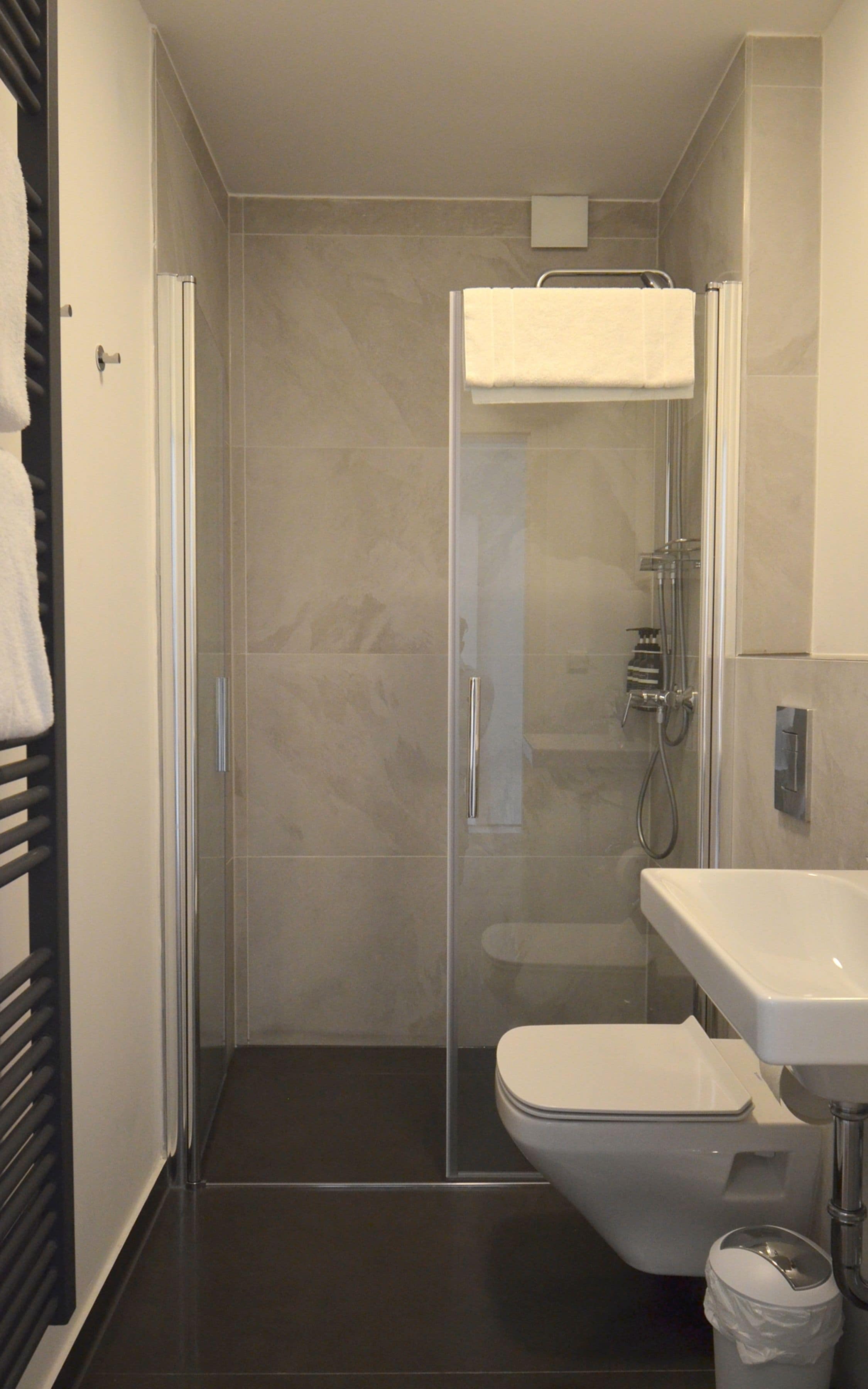 A modern bathroom with a glass-enclosed shower, a white toilet, and a sink with a mirror.