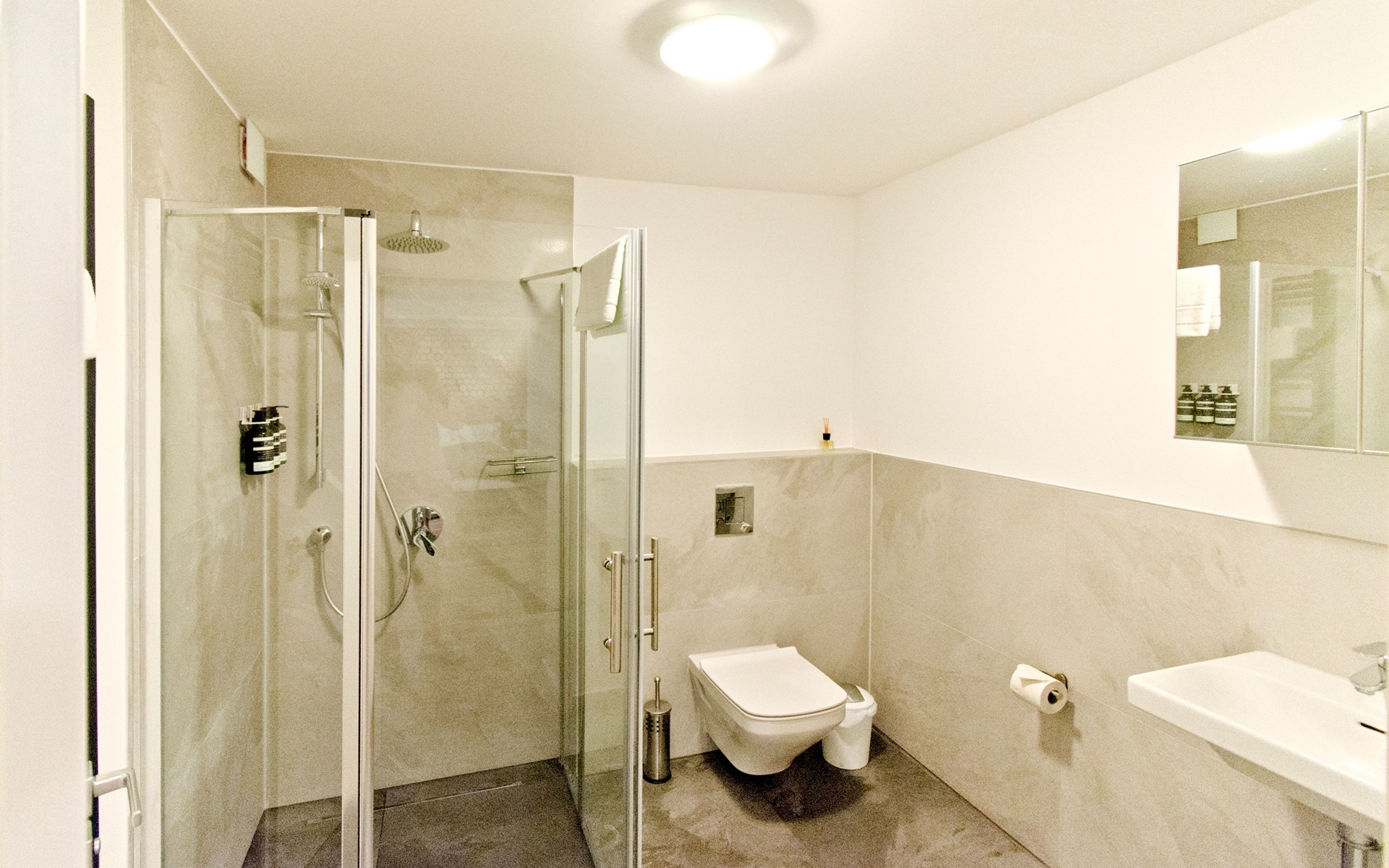 Un baño moderno con ducha de vidrio, inodoro y lavamanos.