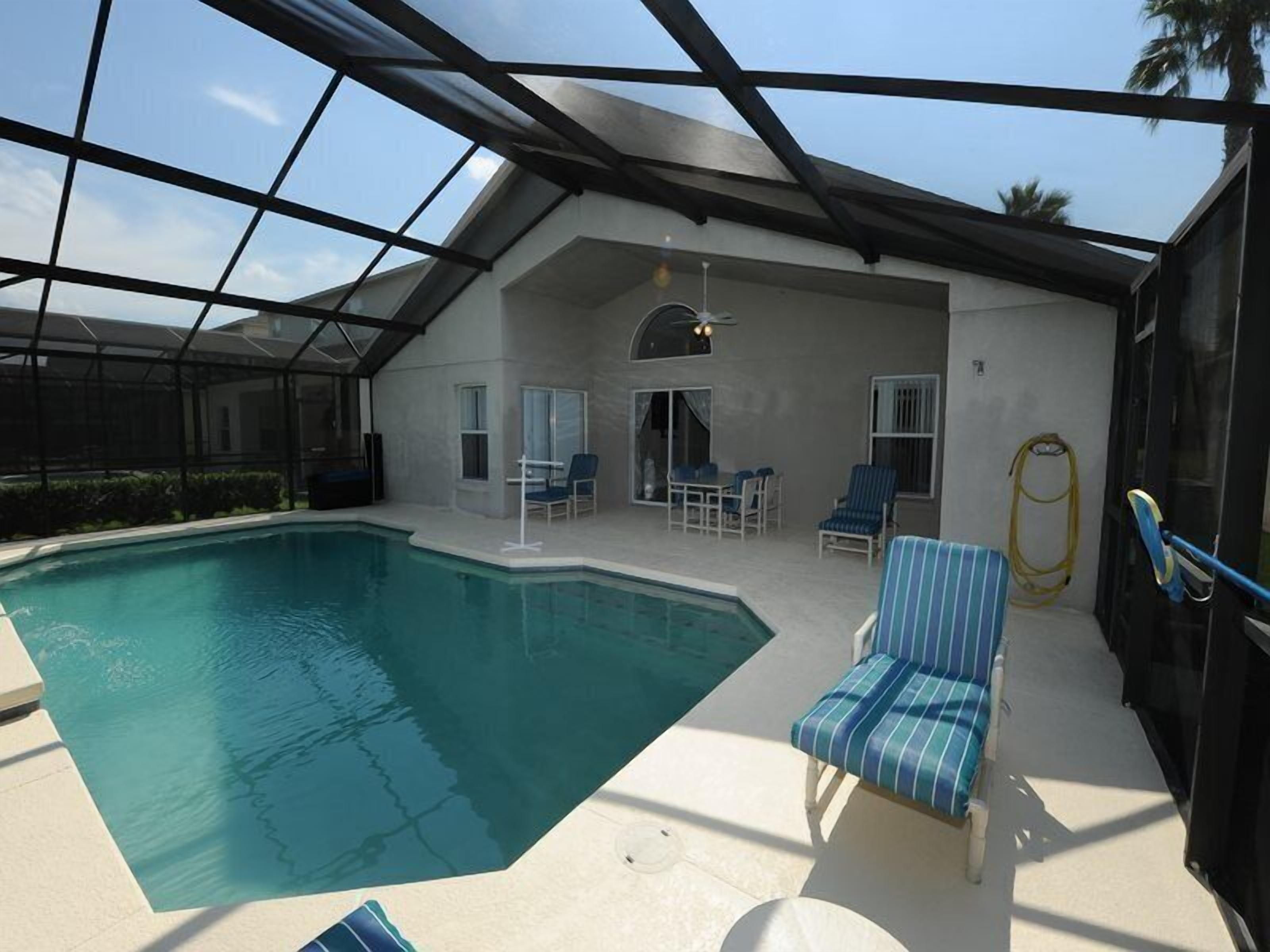 Ein Innenpool mit überdachter Terrasse, Liegestühlen und Deckenventilator.