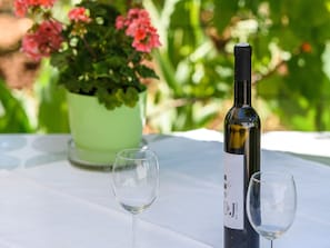 A wine bottle and two glasses on a table with a potted plant in the background. - Apartments Beba - Peaceful Location (Trogir)