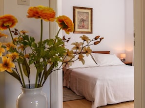 A bedroom with a bed, a bedside table with a lamp, and a framed picture on the wall.