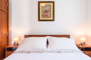 A neatly made bed with white linens, two bedside lamps, and a framed artwork above the headboard. - Apartments Beba - Peaceful Location (Trogir)