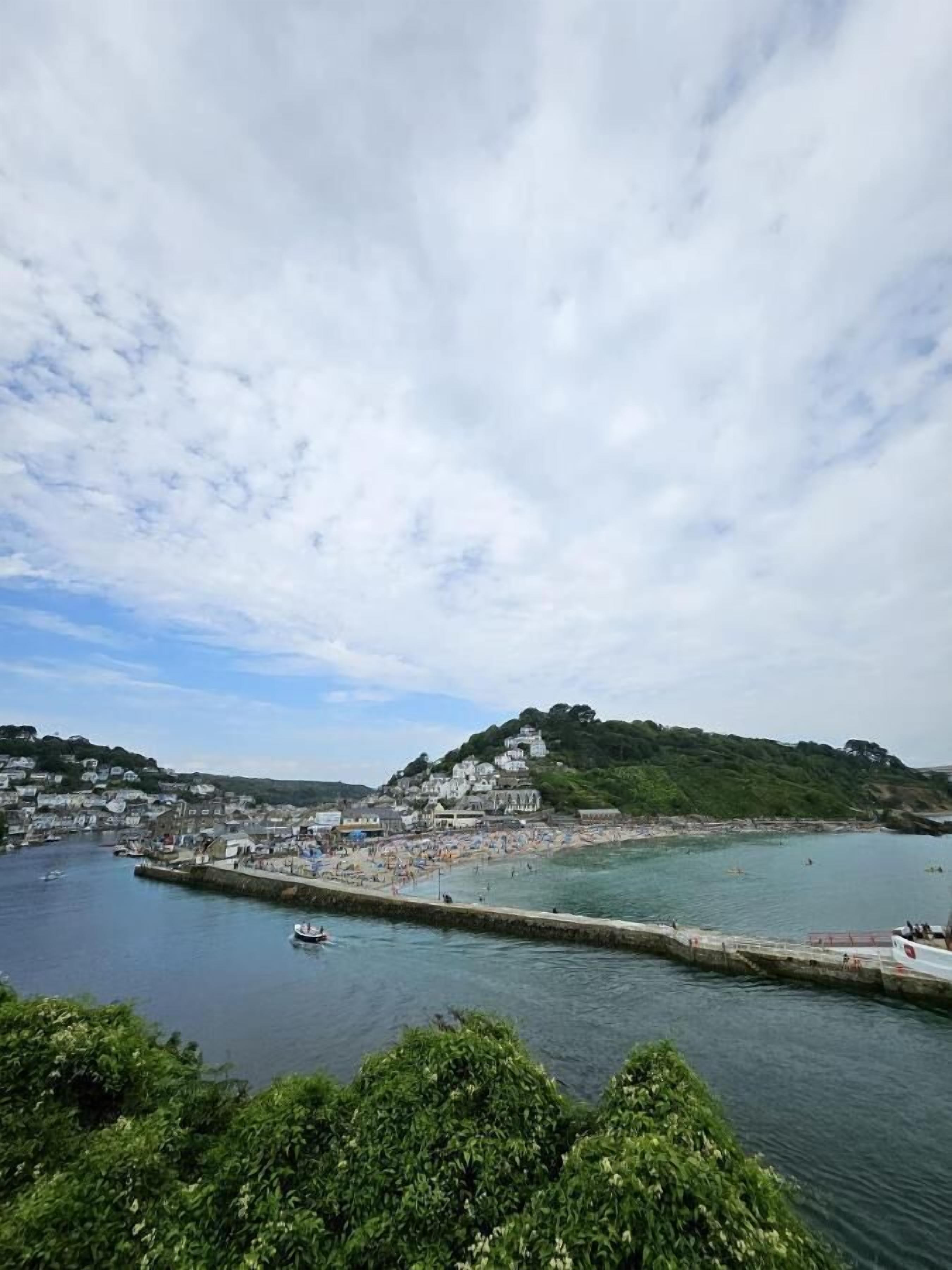A coastal town with a harbor, a beach, and buildings on a hillside.
