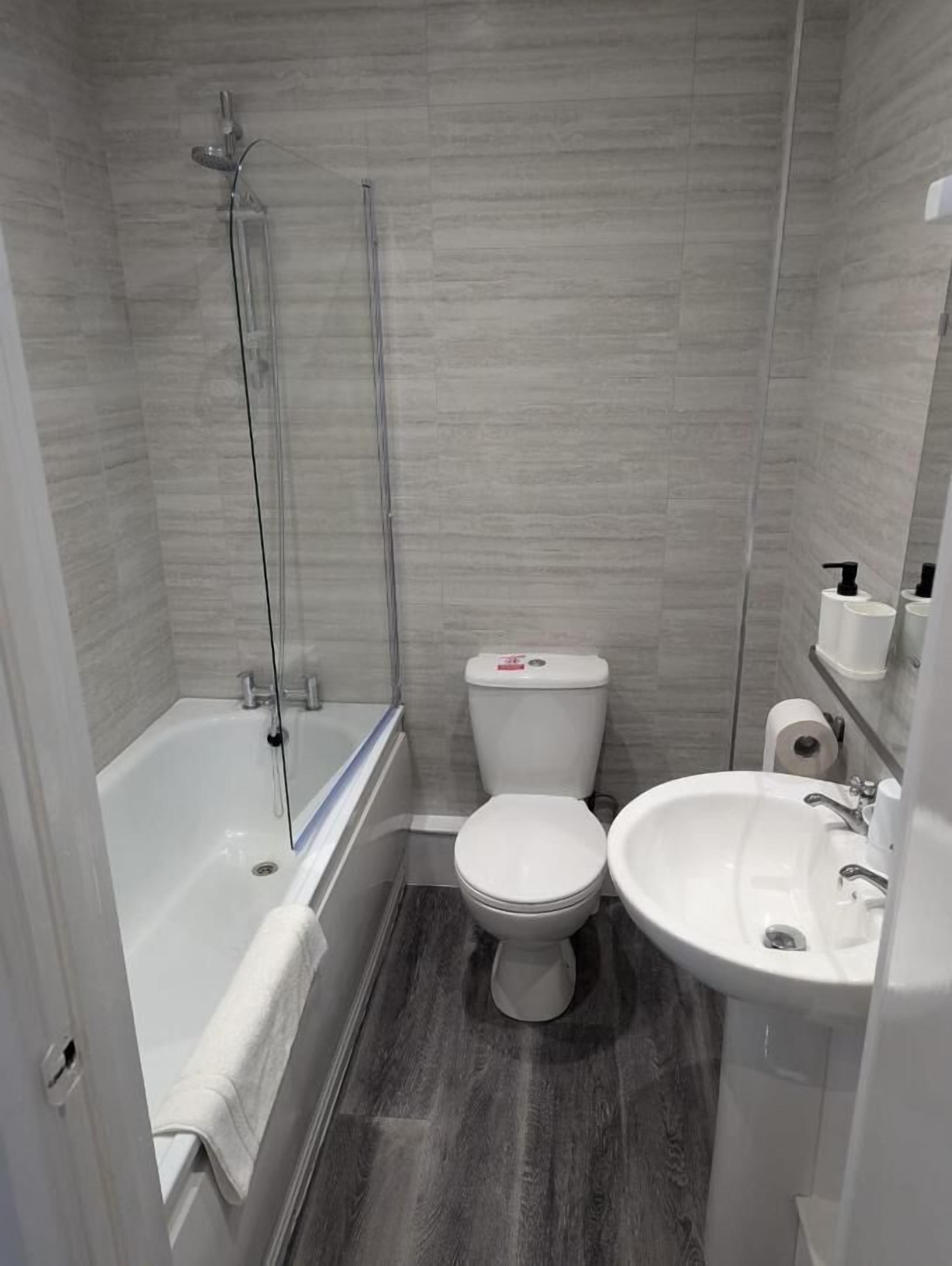 Et moderne badeværelse med badekar, toilet og håndvask.