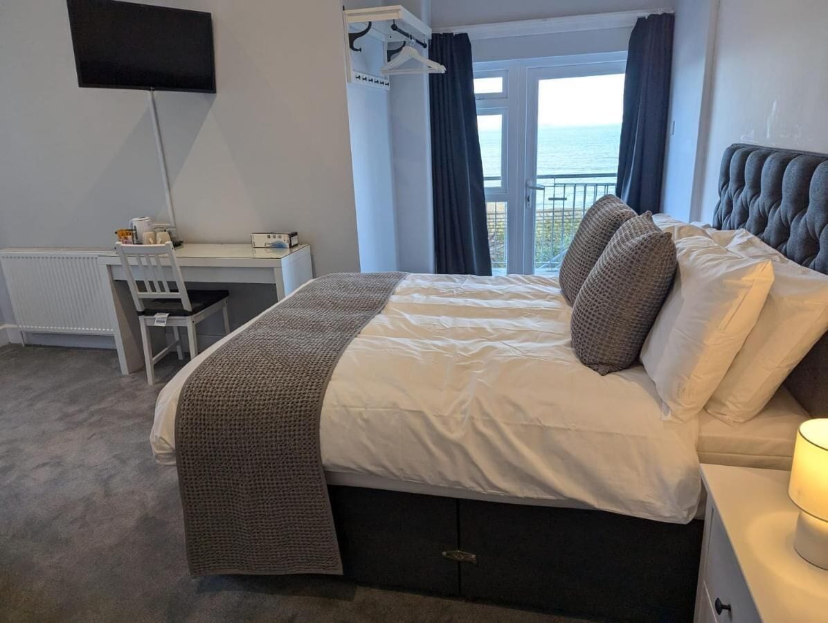 A bedroom with a bed, a desk, and a TV.