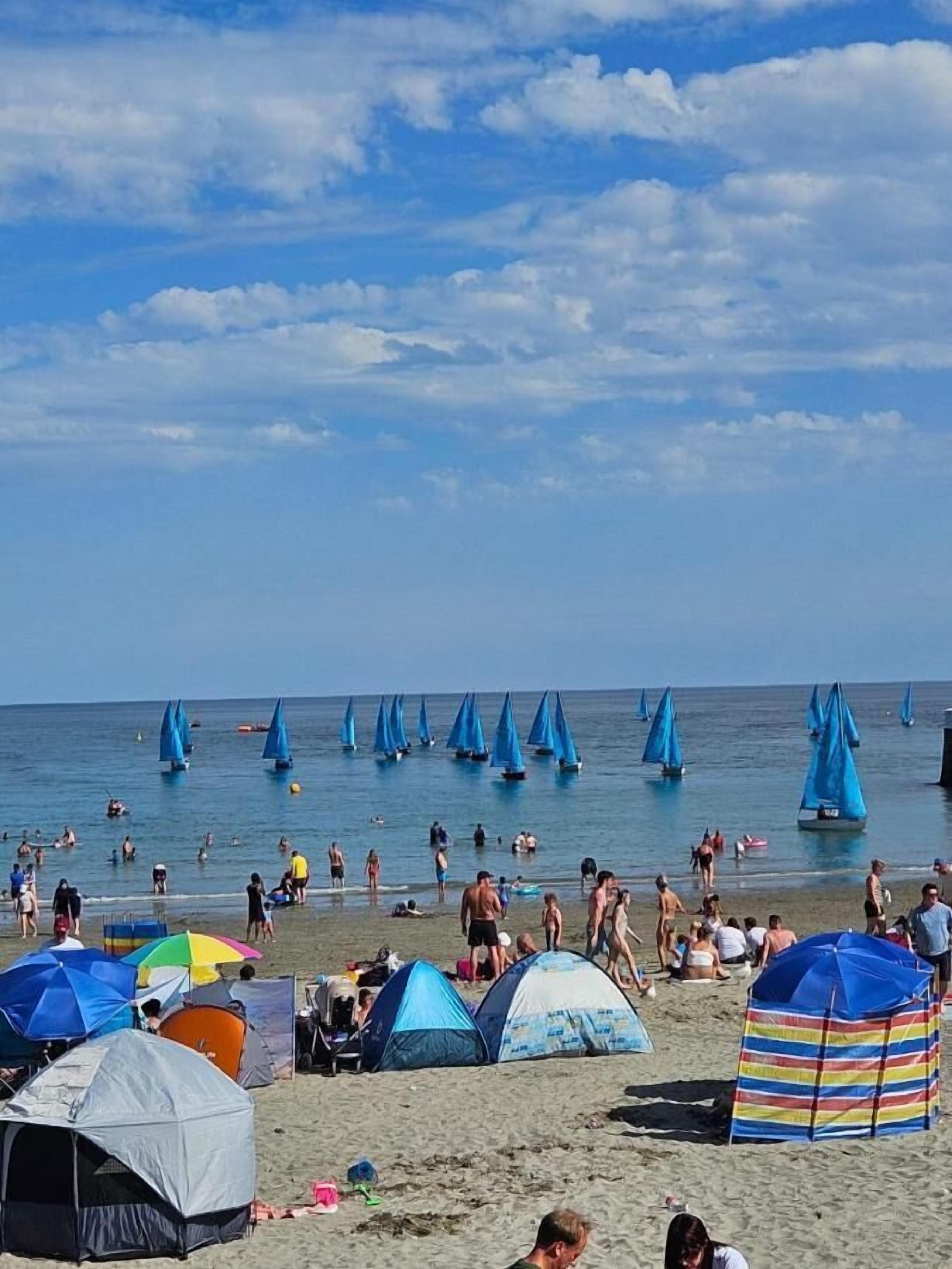 A beach with tents and sailboats.