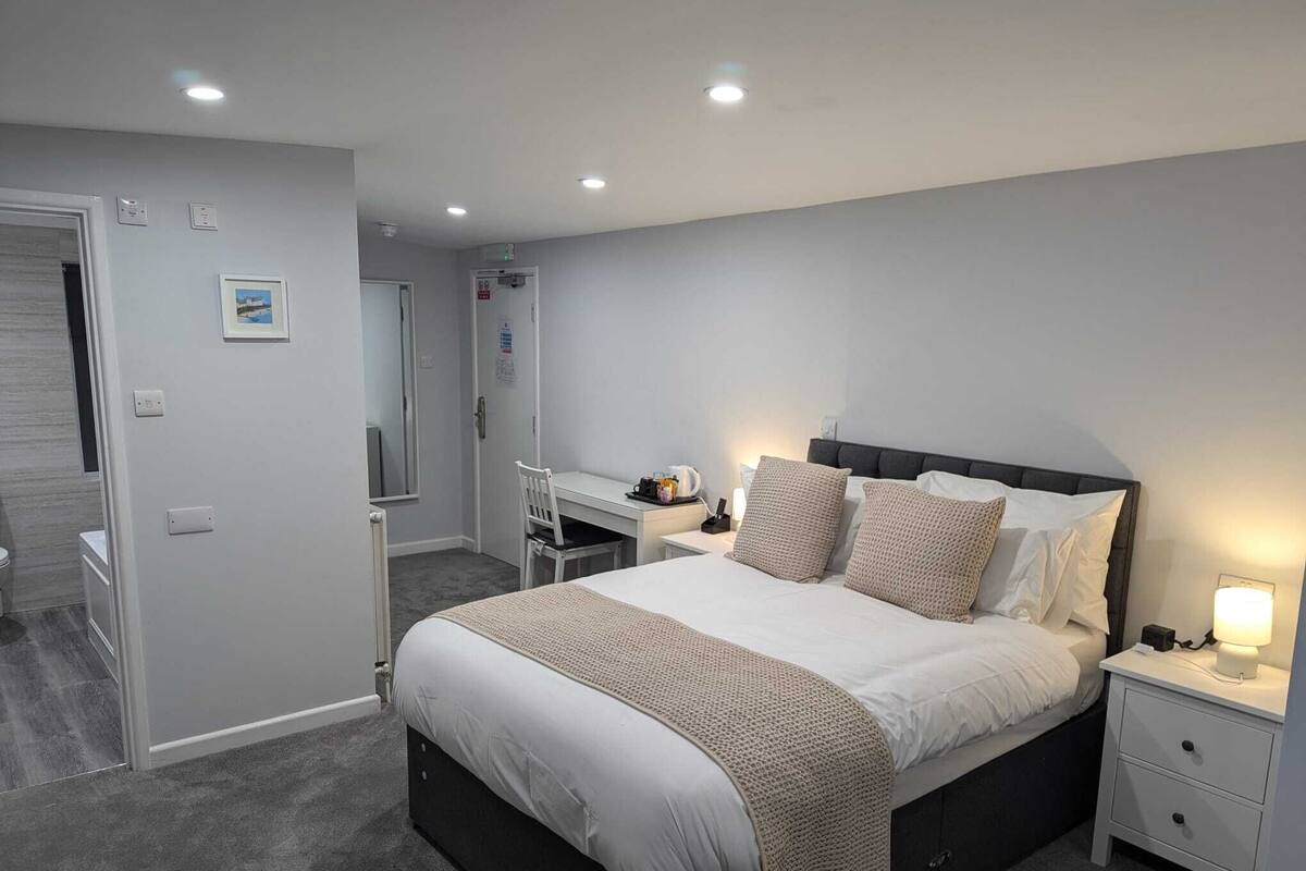 Um quarto moderno com uma cama grande, uma escrivaninha e uma cadeira.