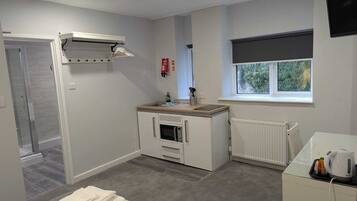 A compact kitchen with a built-in oven, a window with a view, and a radiator.