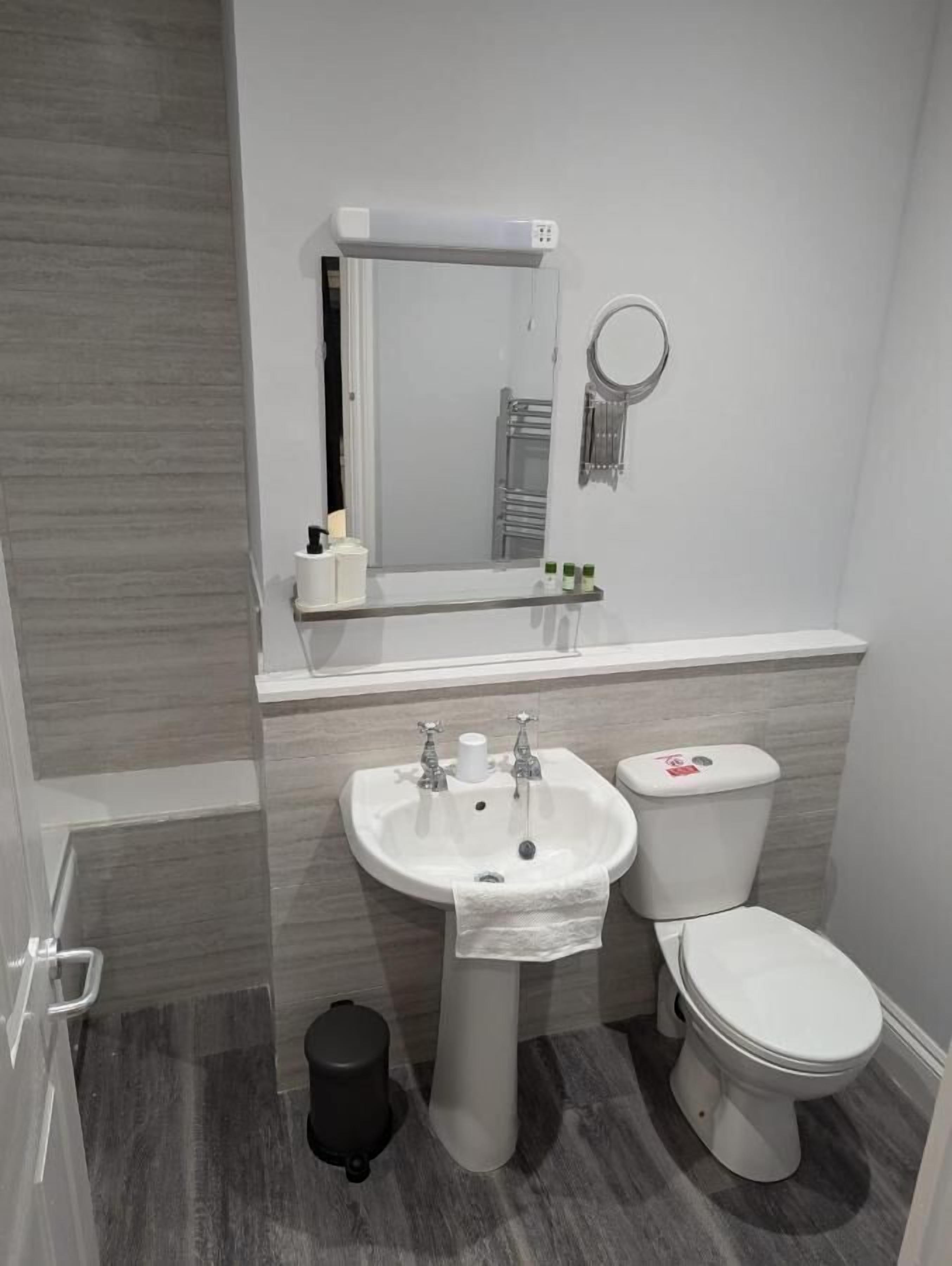 A modern bathroom with a white sink, toilet, and mirror.