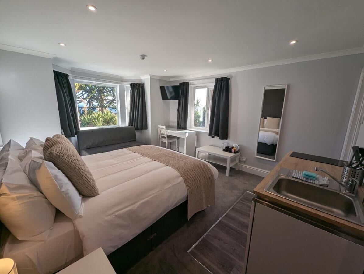 Een moderne hotelkamer met een groot bed, een bureau, een stoel, een televisie en een kleine kitchenette.
