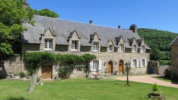 A stone building with a sloped roof, multiple windows, and a well-maintained lawn.