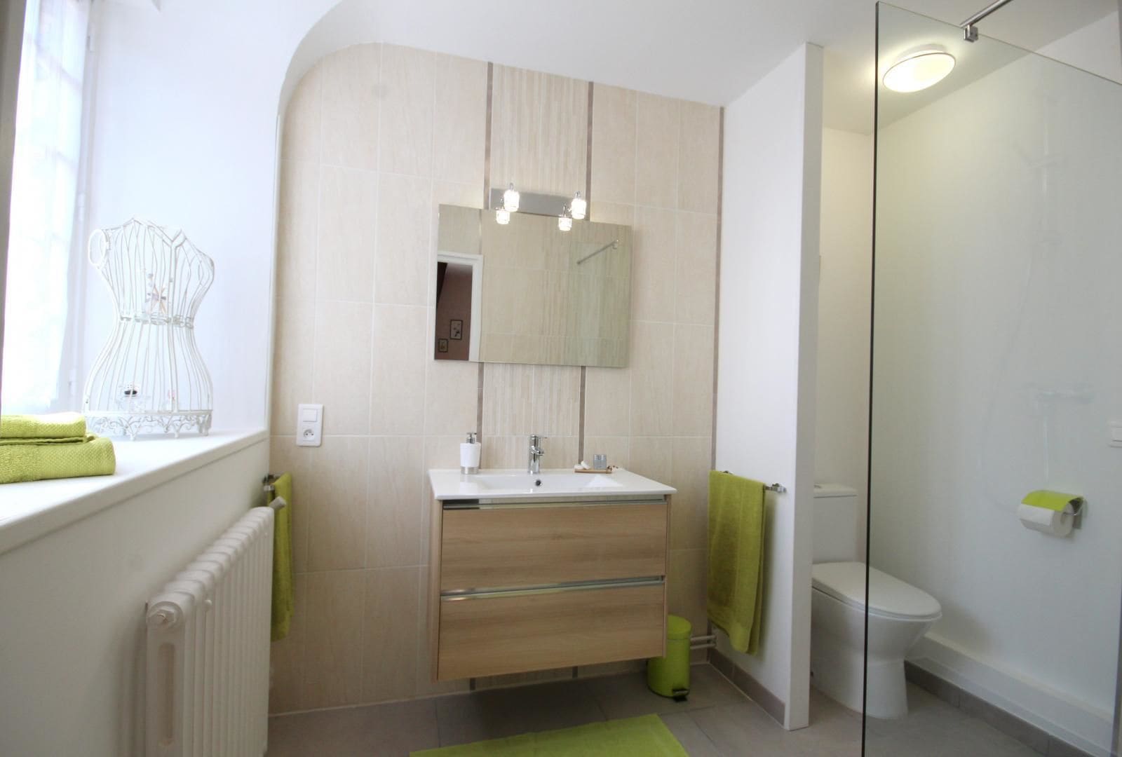 Une salle de bain moderne avec une douche à parois de verre, un lavabo blanc et un meuble-lavabo en bois.