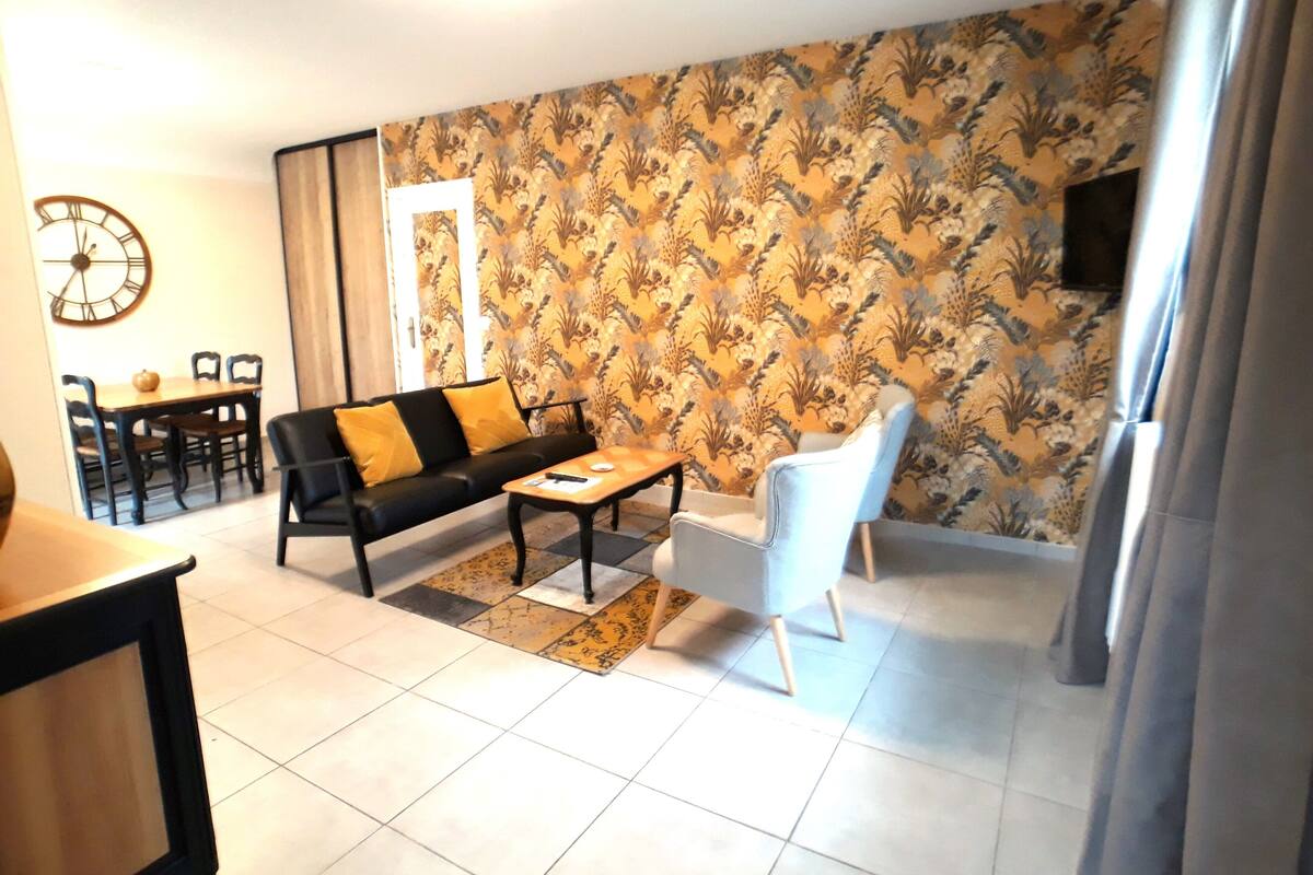 Uma sala de estar com sofá, mesa de centro e uma área de jantar com cadeiras e mesa.