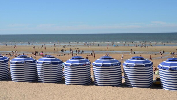 Una playa con sombrillas a rayas y una orilla arenosa.