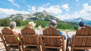 Four wooden Adirondack chairs facing a mountain view. - Recently Remodeled 2 Br Condo at the Plaza (Crested Butte)