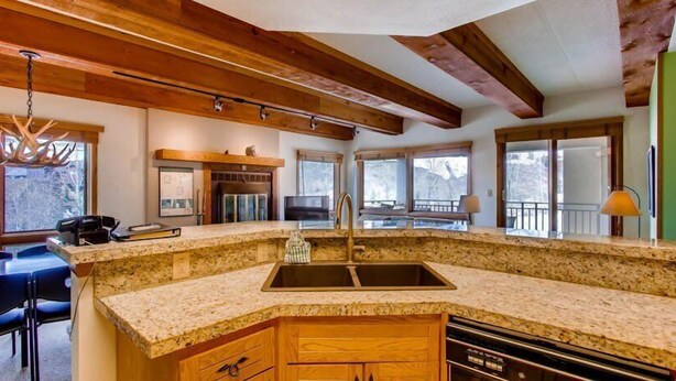 A kitchen with granite countertops, wooden cabinets, a built-in oven, and a large window.