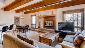 A spacious living room with a fireplace, a television, and a dining area with chairs and a table.