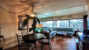 A dining area with a round table and chairs, a sofa, and a coffee table. - Landfall Towers 34 Minium 1 Bedroom Condo by RedAwning (South Padre Island)