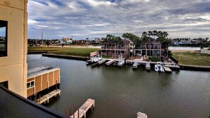 A waterfront property with a dock, a marina, and a residential building with multiple stories and balconies. - Landfall Towers 34 Minium 1 Bedroom Condo by RedAwning (South Padre Island)