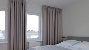 A hotel room with a bed, a window, and curtains. - Chopin Apartments Eco (Warsaw)