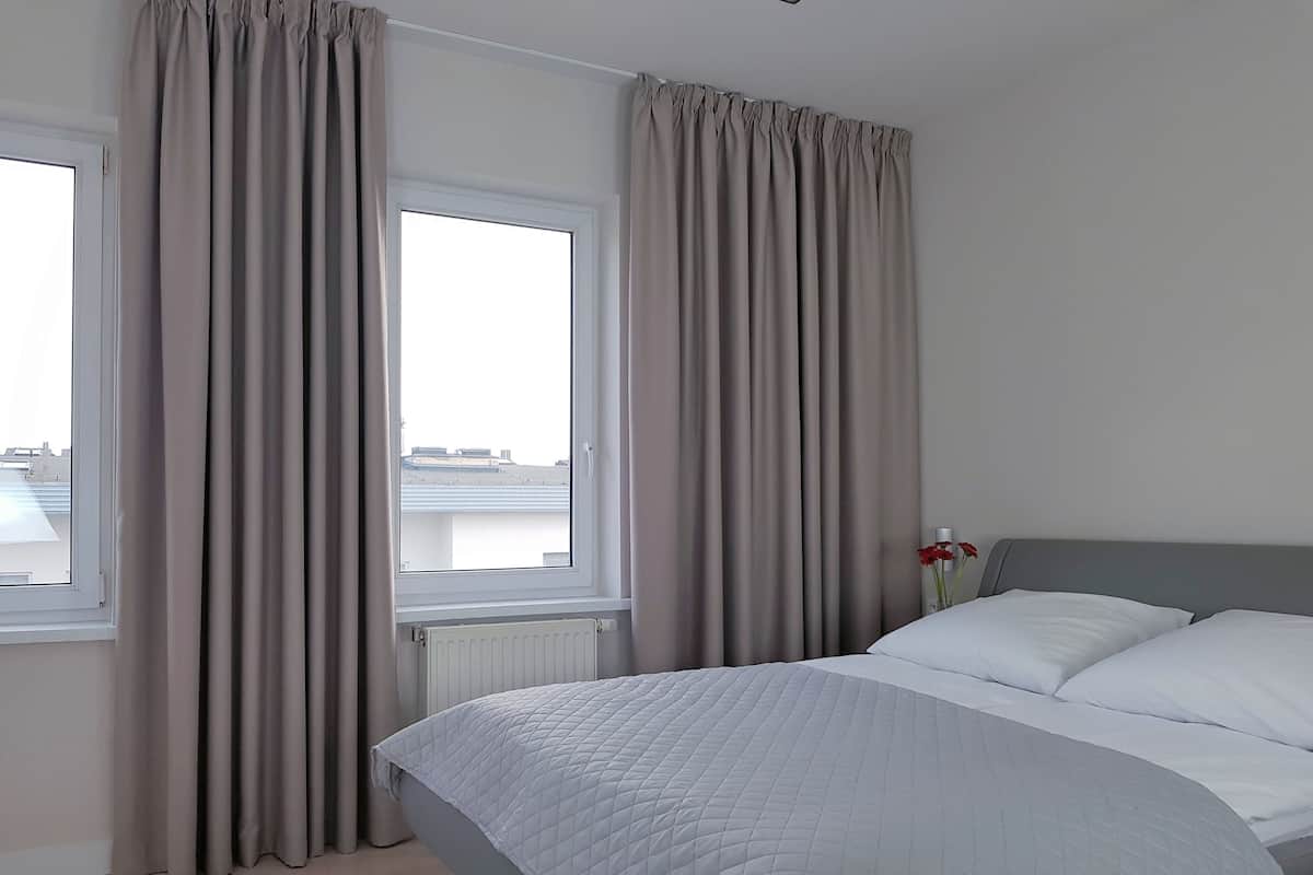 A hotel room with a bed, a window, and curtains.