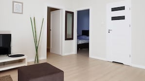 A modern hotel room with a flat-screen TV, a small seating area, and a bed with a headboard. - Chopin Apartments Eco (Warsaw)