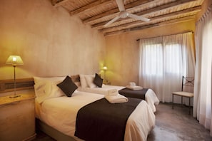 A hotel room with two beds, a wooden ceiling, a chair, and a window with curtains. - Posada Borravino (Chacras de Coria)