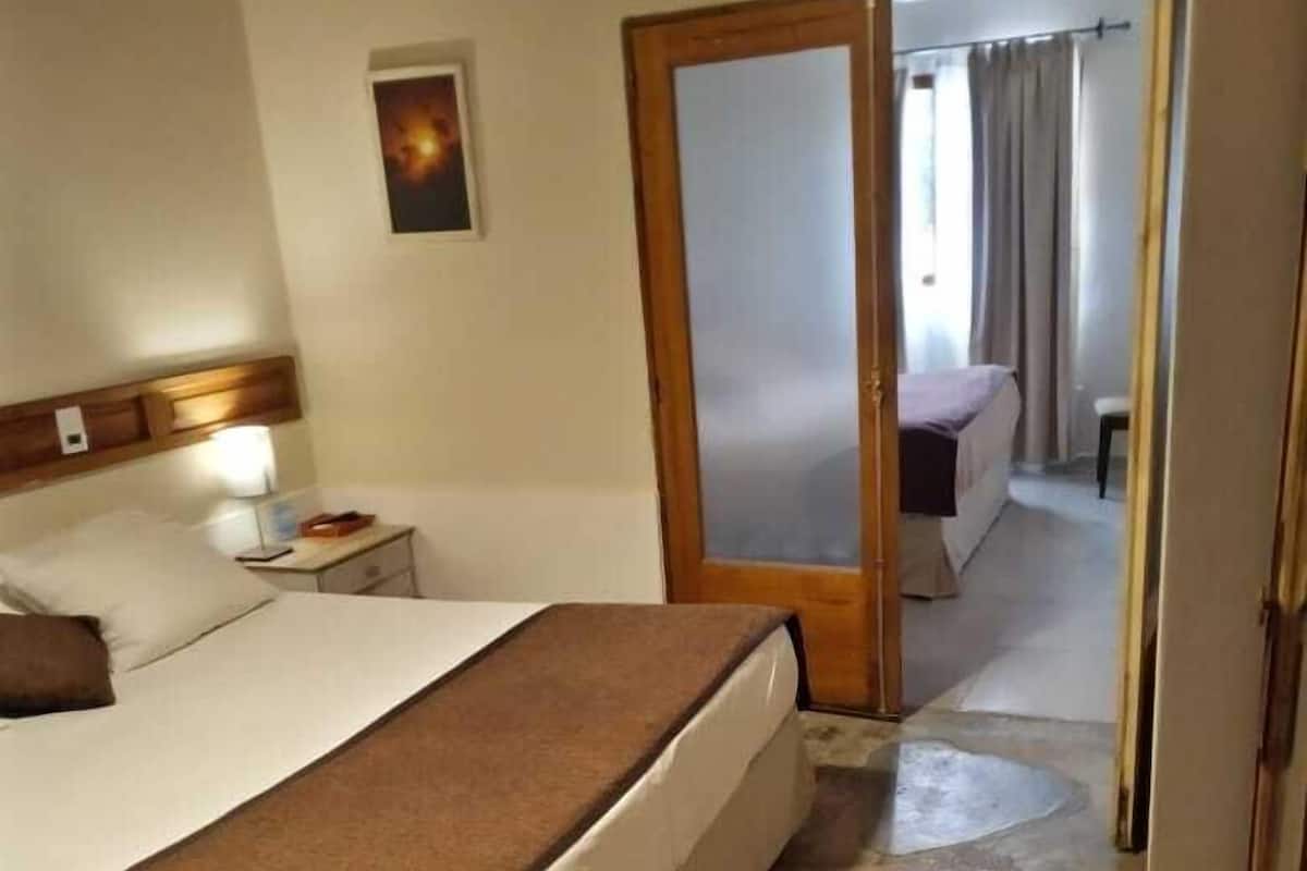 A hotel room with a bed, bedside table, and a door leading to a bathroom.