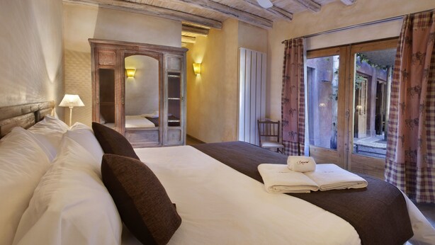 Een hotelkamer met een groot bed, een houten garderobe, een raam met gordijnen en uitzicht op het omliggende landschap.