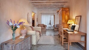 Een gezellige woonkamer met een bank, fauteuils, een houten bureau en een laptop.