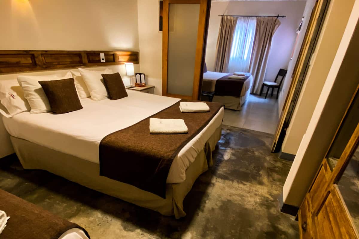 A hotel room with a large bed, a smaller bed, a desk, and a television.