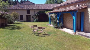 A house with a tiled roof, a covered patio area, and a lawn with two folding chairs.