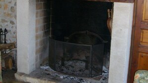 A fireplace with a stone wall, a wooden mantel, and a framed artwork above it.