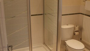 Une salle de bain avec une douche à parois de verre, des toilettes et un porte-serviettes.