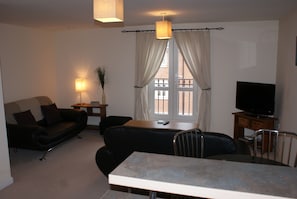 Relax in this stylish living room with a black leather sofa, armchair, and dining table.
