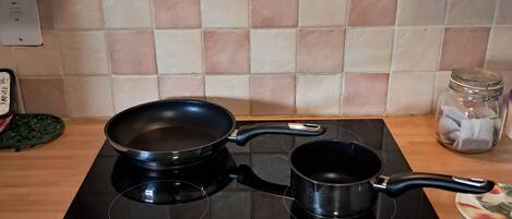 A kitchen with a black induction cooktop, two black pots, and a green spatula on the counter.