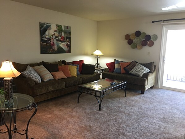 A living room with two sofas, a coffee table, a lamp, and a painting on the wall.