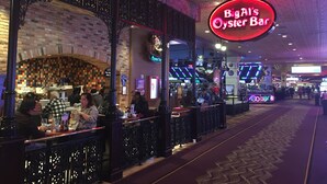 Eine Bar im Innenbereich mit einem Neon-Schild mit der Aufschrift 'Big Al's Oyster Bar' und einer Ziegelwand mit einem farbenfrohen Mosaik.