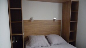 A bed with a wooden headboard and two pillows, flanked by shelving units with storage space.