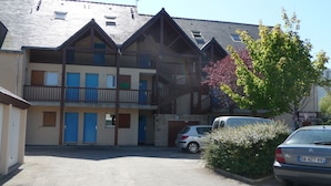 A multi-story residential building with balconies and a parking area.