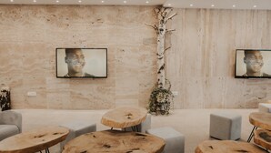 A modern interior with a stone wall, wooden tables, and grey seating. - Aparthotel Centar Sarajevo (Sarajevo)