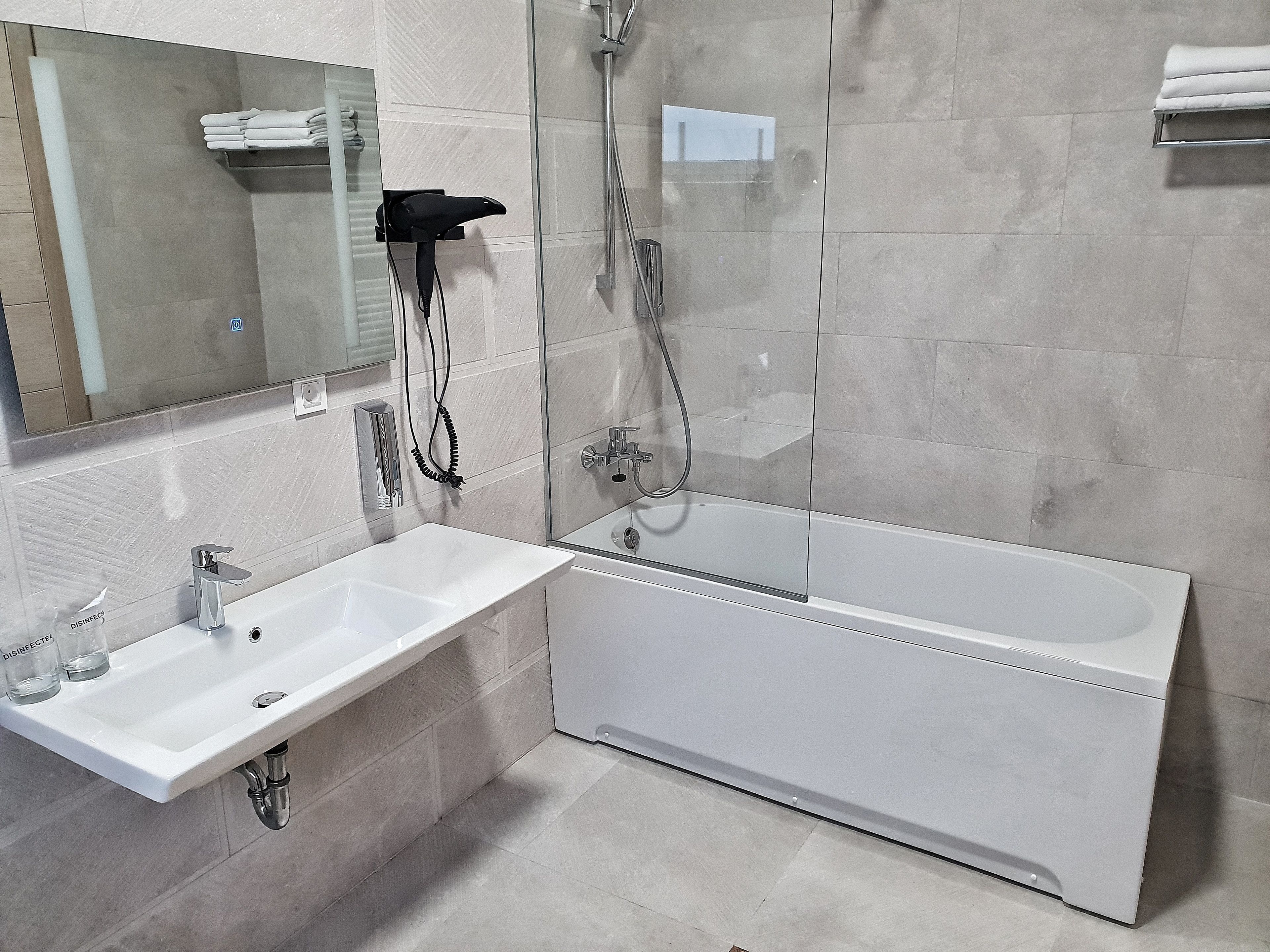 A modern bathroom with a white sink, mirror, and bathtub.