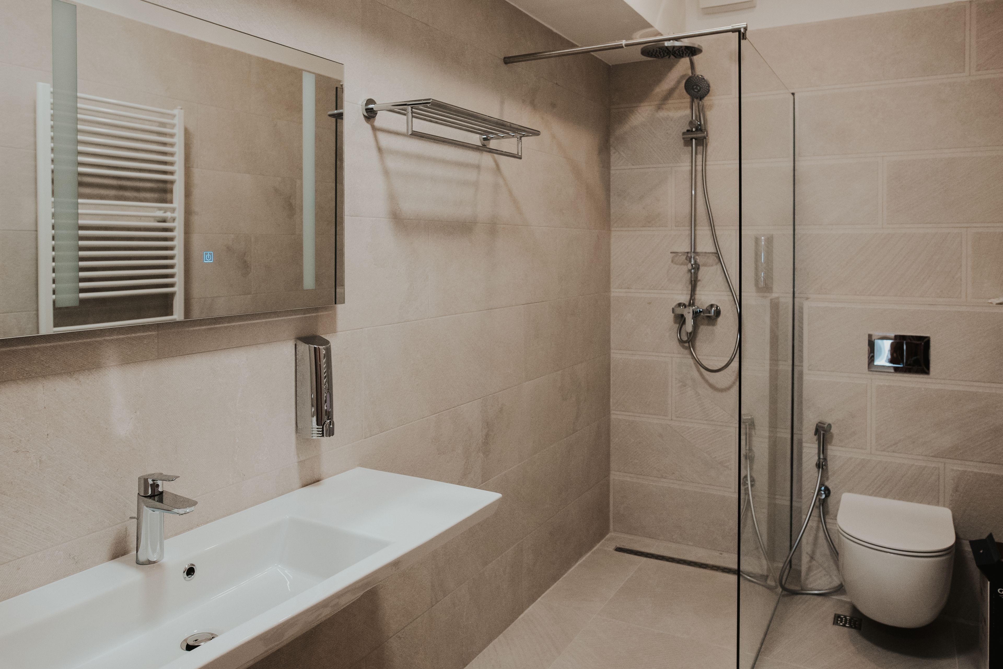 A modern bathroom with a white sink, a glass-enclosed shower, and a toilet.