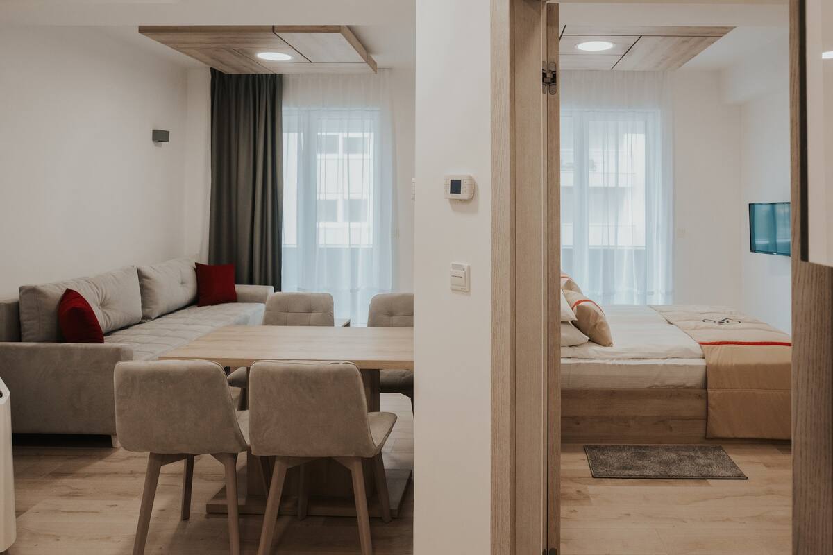 A modern, compact living space with a sofa, dining table, and a bed.