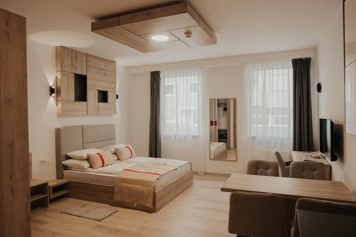 A modern hotel room with a bed, a desk, and a chair.